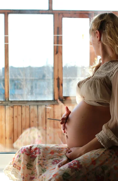 Těhotná žena sedí u okna — Stock fotografie