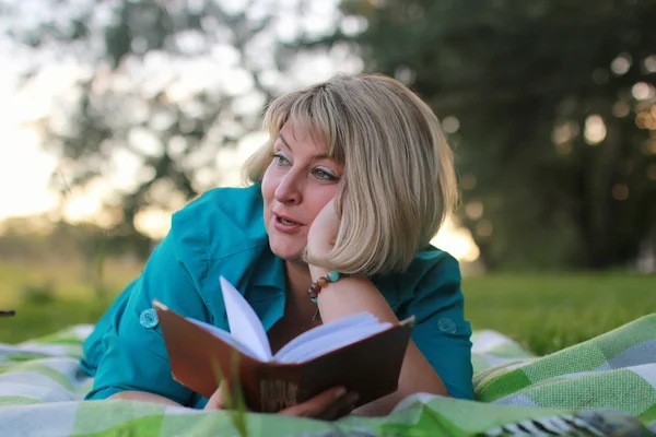 Mujer en el parque con libro sobre la hierba —  Fotos de Stock
