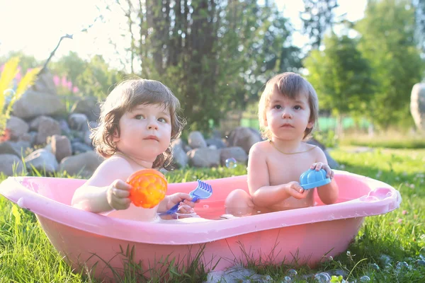 Gemelos chico y chica en baño agua al aire libre — Foto de Stock