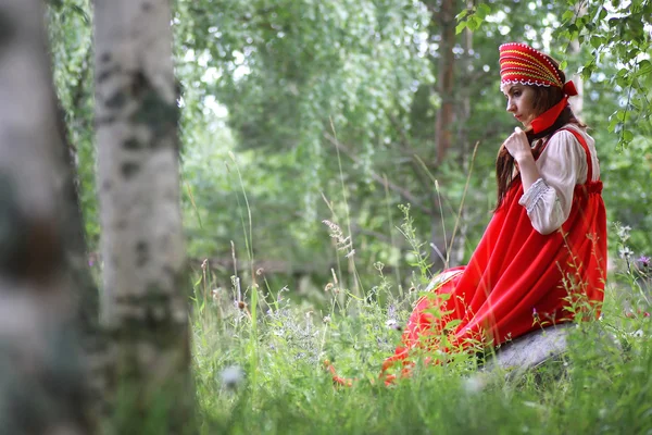 Слов'янська в традиційному одязі сидить в природі — стокове фото