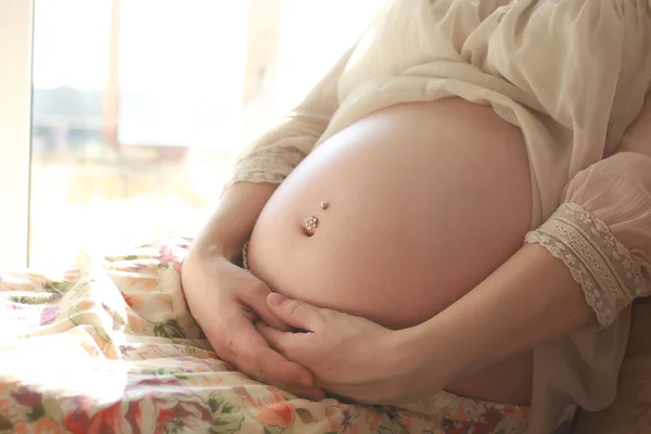Беременная женщина сидит у окна — стоковое фото