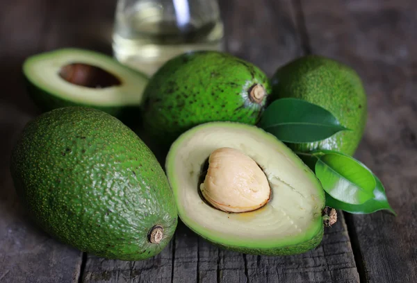 Aguacate y aceite sobre fondo de madera — Foto de Stock