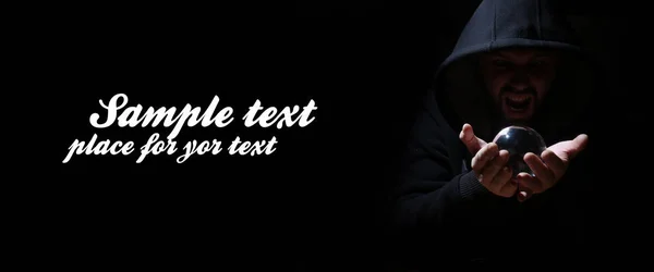 Man in a black hood with cristal ball and empty space for text — Stock Photo, Image