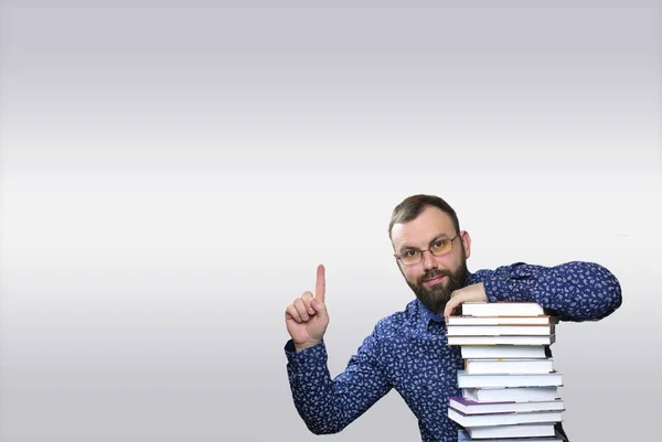 Взрослый бородач со стопкой книг в библиотеке — стоковое фото