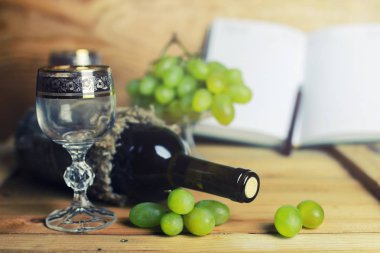 üzüm ve şarap şişesi kitap ile ahşap masa