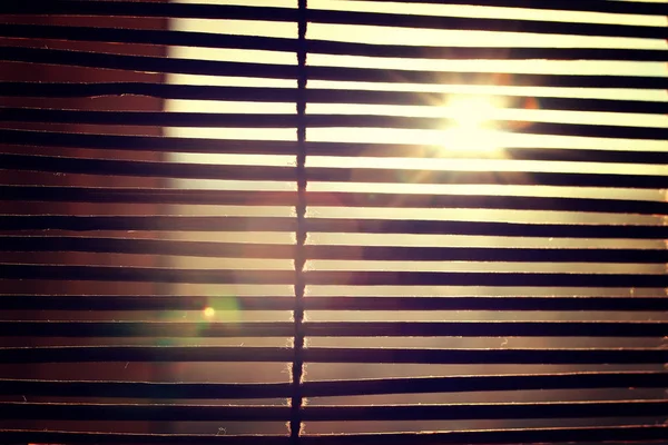 Abbagliamento dalla luce solare brillante attraverso le tende Rom in legno — Foto Stock