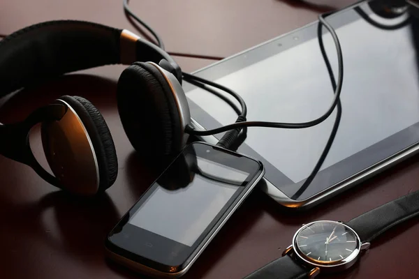 Fejhallgató-ra egy asztal mellett a tabletta és egy óra — Stock Fotó