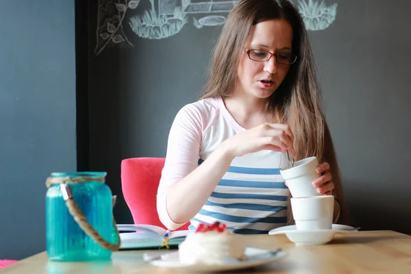 Chica en un café para una taza de café con el cuaderno —  Fotos de Stock