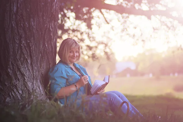 Female in the park on sunset with book — Stock Photo, Image