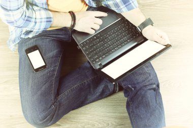 Yerde dizüstü bilgisayarı olan bir adam var.