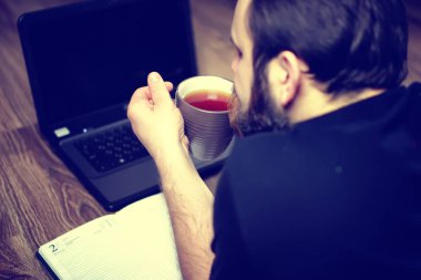 Sakallı yakışıklı adam yalan yere bir ekose ve çalışma dizüstü sarılmış