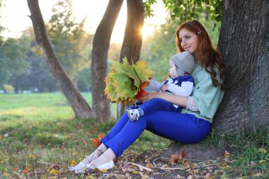 Kızıl saçlı kız oğlu ile sonbahar yaprakları