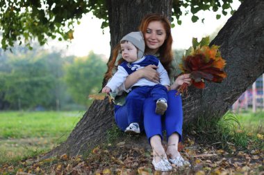 Kızıl saçlı kız oğlu ile sonbahar yaprakları