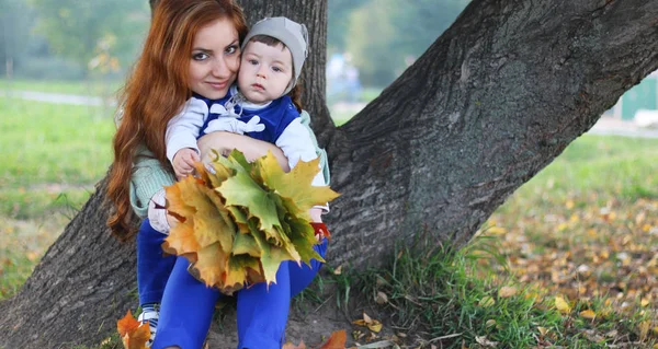 Kızıl saçlı kız oğlu ile sonbahar yaprakları