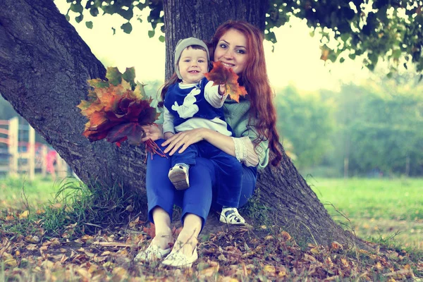 Рыжая девушка с сыном Осенние листья — стоковое фото