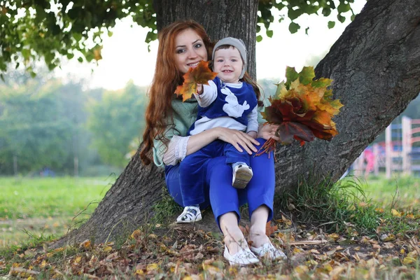 Руда дівчина з сином Осіннє листя — стокове фото