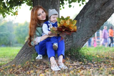 Kızıl saçlı kız oğlu ile sonbahar yaprakları