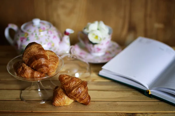 Tasse mit Tee Croissant Buch — Stockfoto