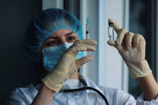 Медсестра держит в руках шприц и ампулу — стоковое фото