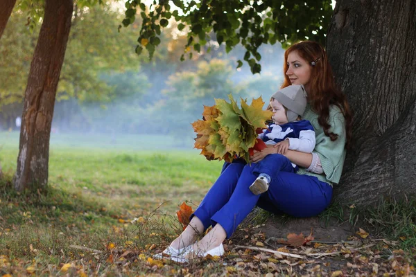 Руда дівчина з сином Осіннє листя — стокове фото