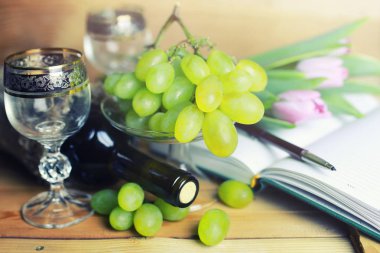 üzüm ve şarap şişesi kitap ile ahşap masa