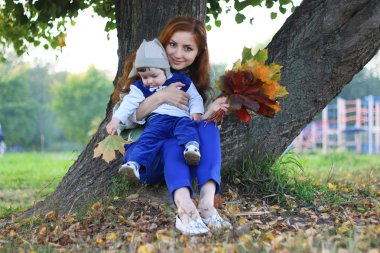 Kızıl saçlı kız oğlu ile sonbahar yaprakları