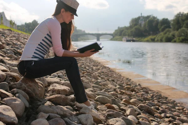 Chica al aire libre leer libro piedra río — Foto de Stock