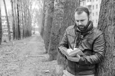 Kışın açık havada kitap okuyan bir adam.