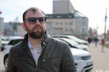 Ceketli ve güneş gözlüklü sakallı adam.