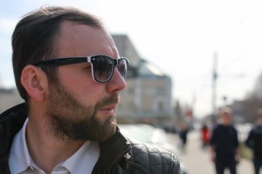 Ceketli ve güneş gözlüklü sakallı adam.