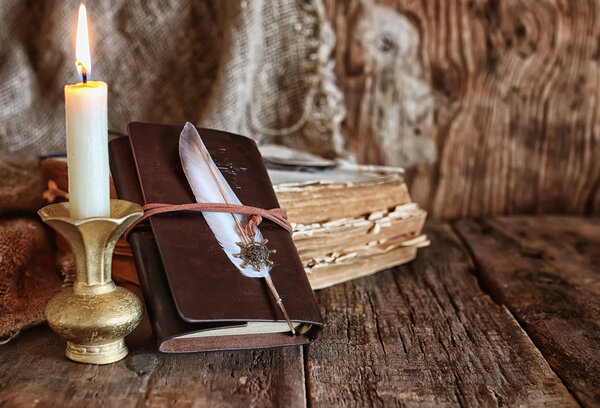 feather and book novel close to the a candle