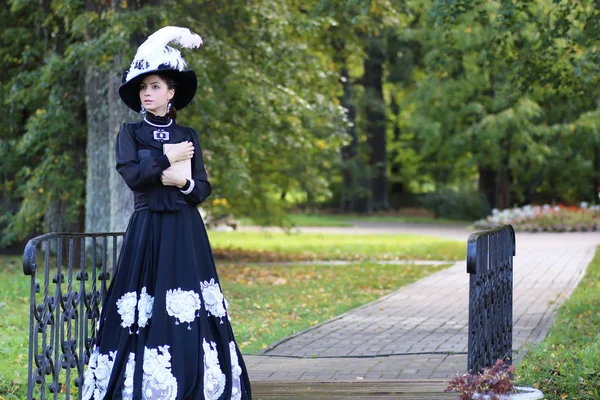 Renaissance vrouw met boek over de brug in het park — Stockfoto