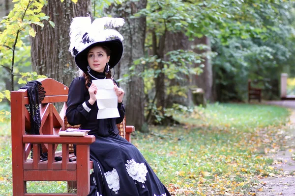 stock image girl in retro dress past century read letter on the bench