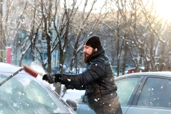 Man cleans snow from the glass at the car — Stock Photo, Image