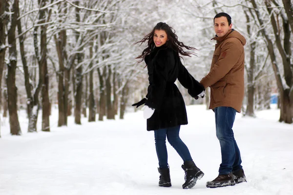 Hermosa pareja joven en un parque cubierto de nieve — Foto de Stock