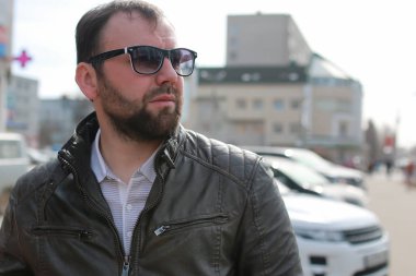 Ceketli ve güneş gözlüklü sakallı adam.