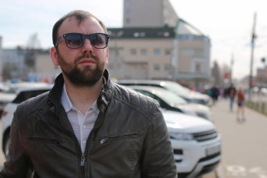 Ceketli ve güneş gözlüklü sakallı adam.