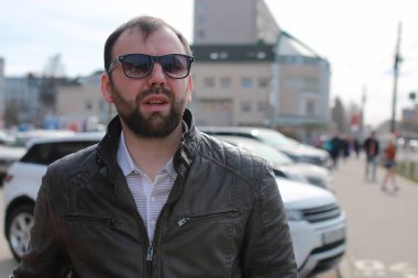 Ceketli ve güneş gözlüklü sakallı adam.