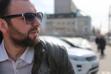 Ceketli ve güneş gözlüklü sakallı adam.