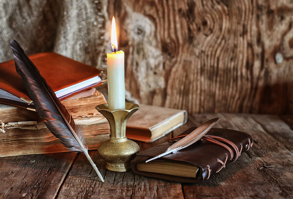 feather and book novel close to the a candle