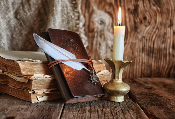 feather and book novel close to the a candle