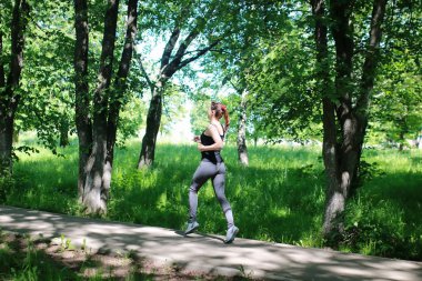 Kadın sporu dışarıda parkta koşuyor.