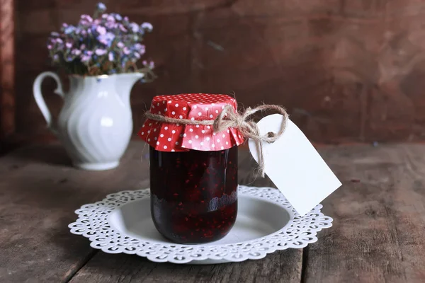 Rustikální domácí marmelády sklenice dřevěné pozadí a květina — Stock fotografie