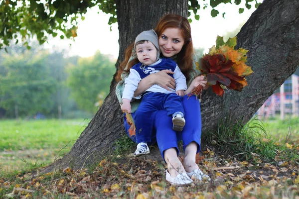 Kızıl saçlı kız oğlu ile sonbahar yaprakları