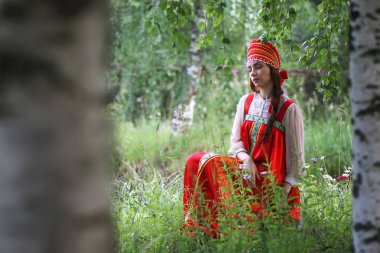Geleneksel elbiseyle Slav doğada oturuyor