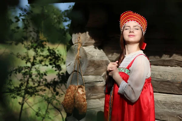 Girl in traditional dress wooden wall — Stock Photo, Image