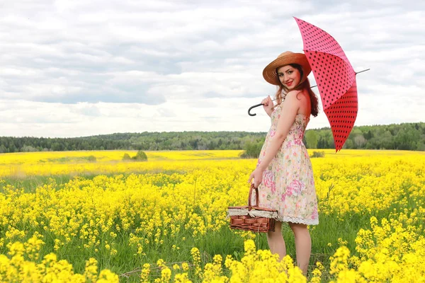 Fille dans un champ de fleurs avec un parapluie et un chapeau — Photo