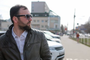 Ceketli ve güneş gözlüklü sakallı adam.