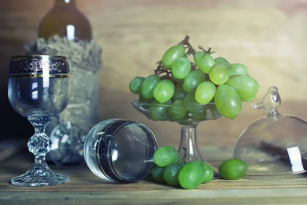 Деревянный стол с винной бутылкой и виноградом — стоковое фото