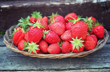 Hasır plaka ahşap arka plan üzerinde çilek